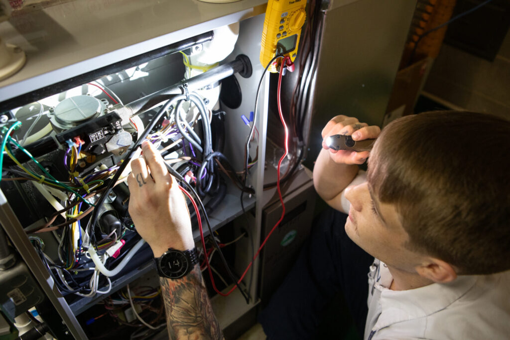 A man is focused on repairing a gas furnace